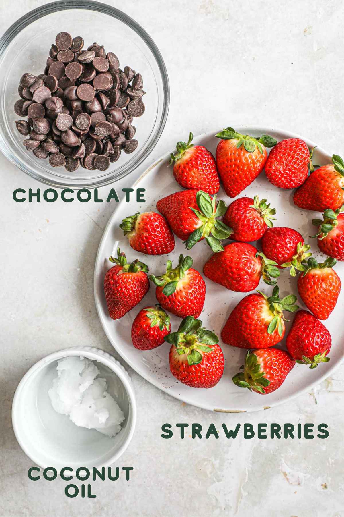 Ingredients to make chocolate covered strawberries, including chocolate, coconut oil, and strawberries.