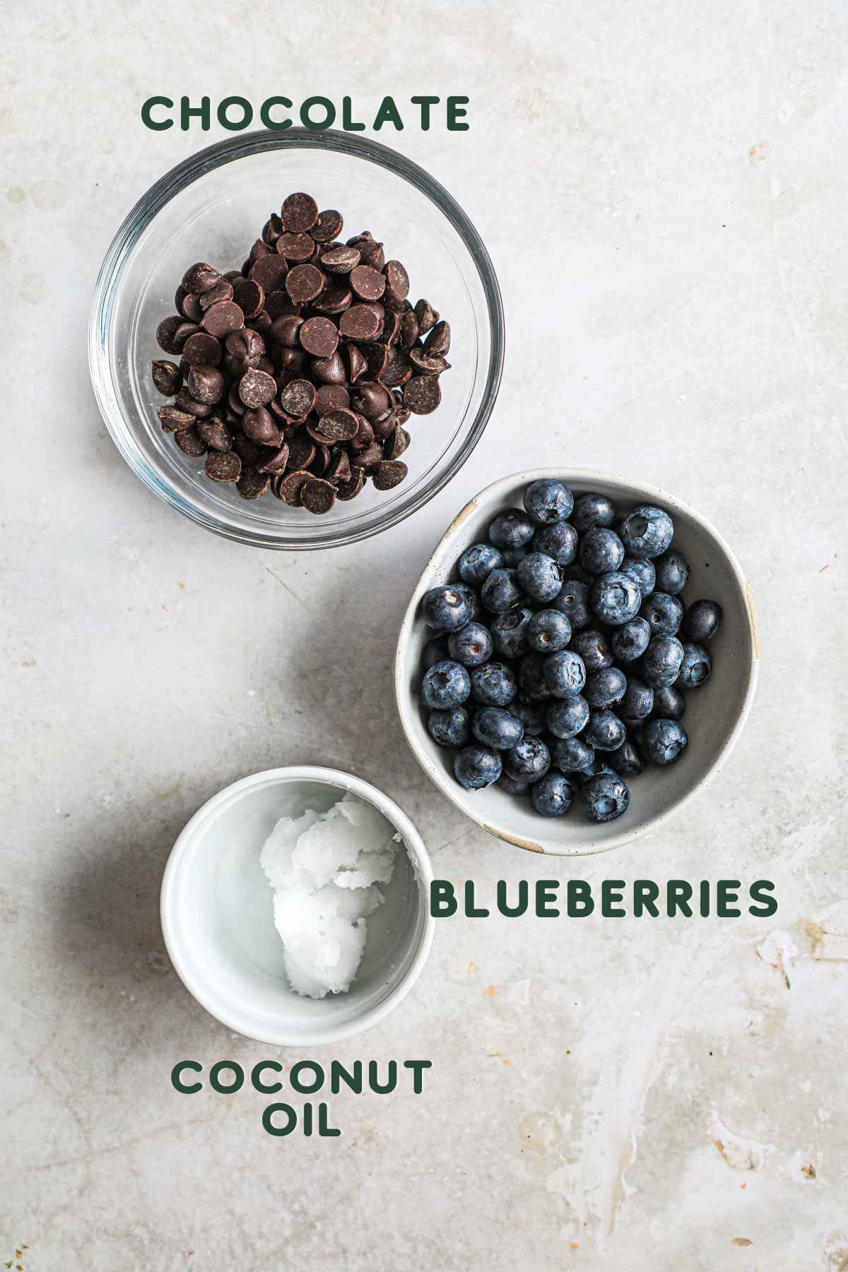 Ingredients to make easy chocolate covered blueberries, including chocolate, coconut oil, and blueberries.
