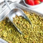 Green tea matcha granola with nuts and seeds scooped on a metal baking sheet.