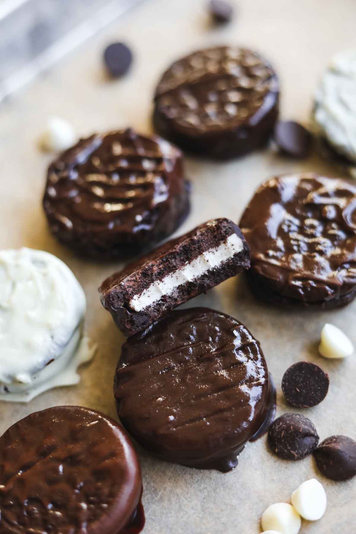 Chocolate-covered Oreos on parchment paper with chocolate chips and white chocolate chips.