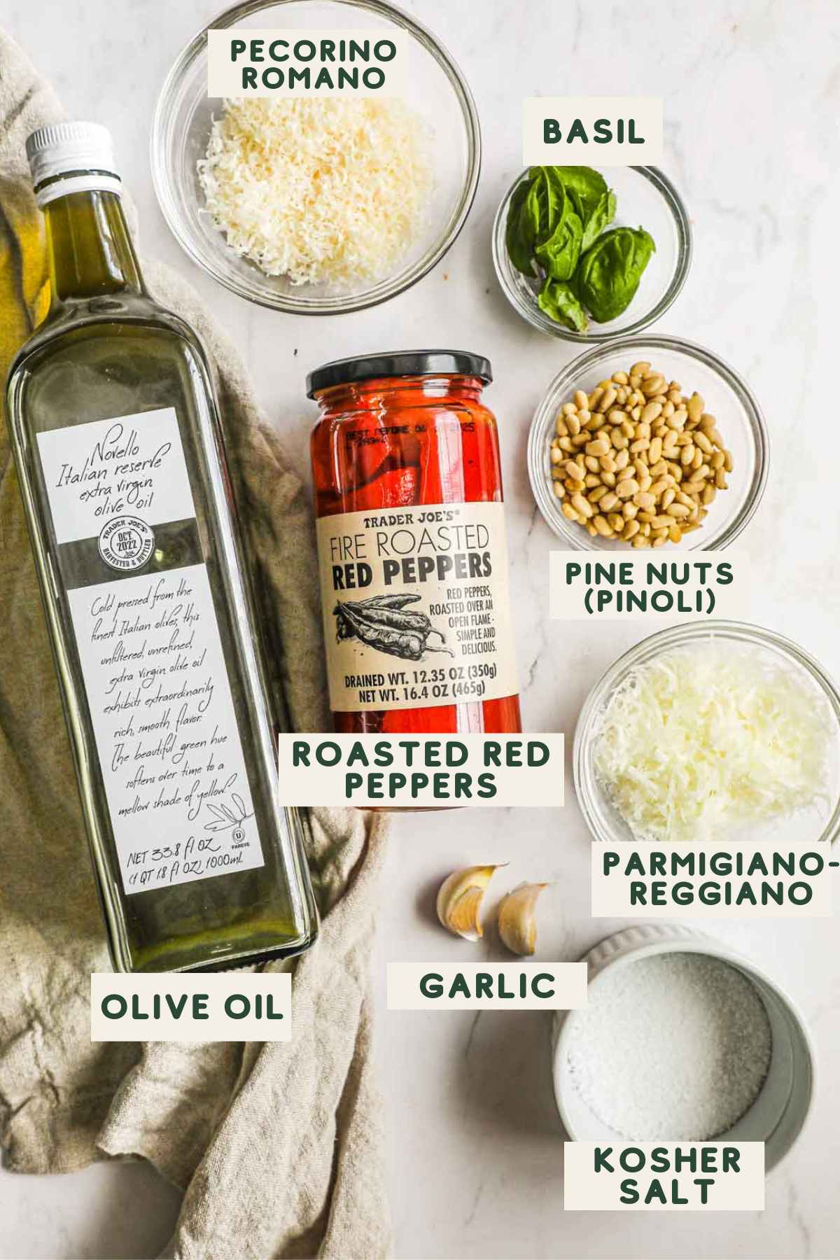 Ingredients to make roasted red pepper pesto, including roasted red peppers, pecorino romano, parmigiano-reggiano, olive oil, basil, pine nuts, and kosher salt.