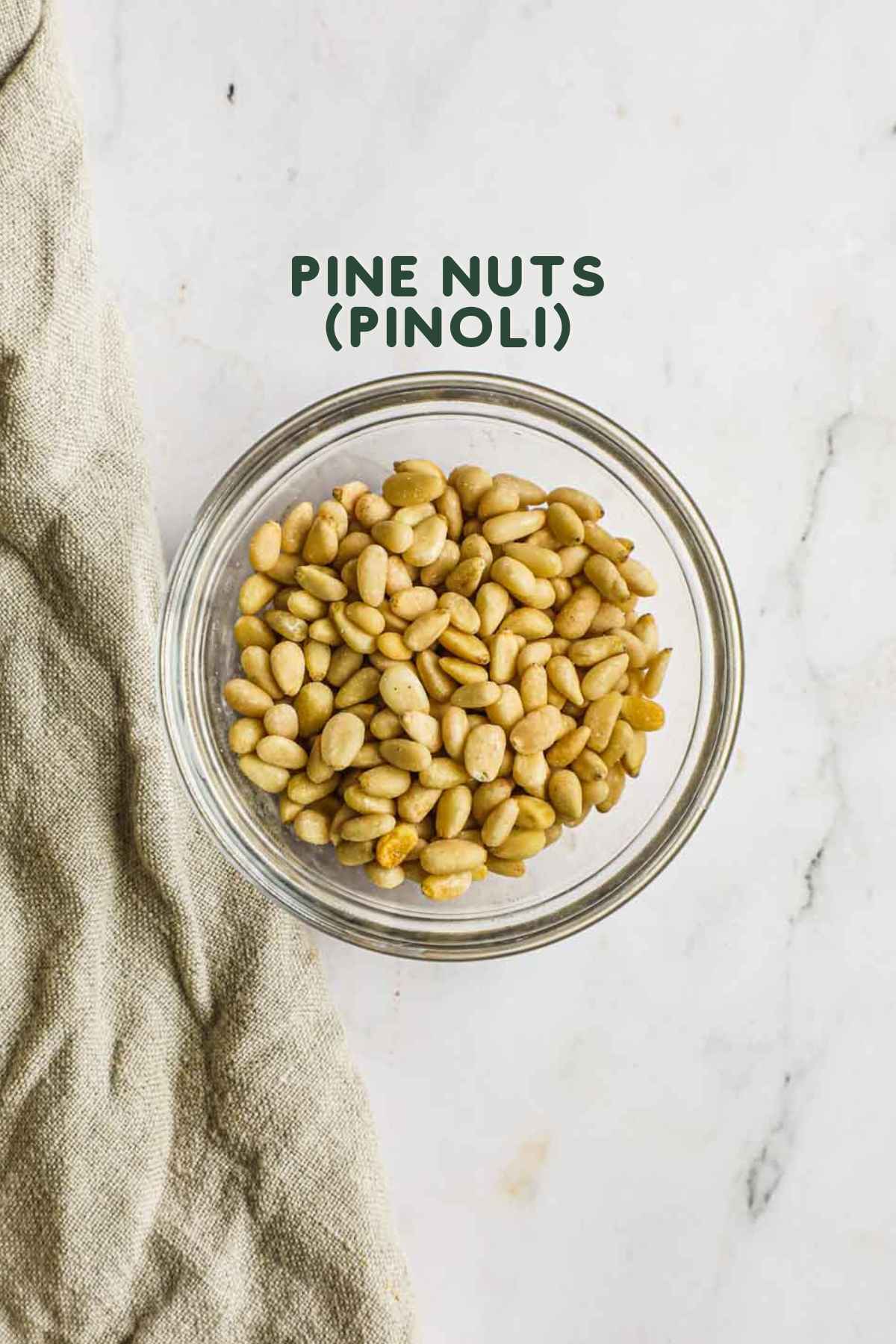 Ingredients to toast pine nuts, including raw pine nuts and a dry skillet.
