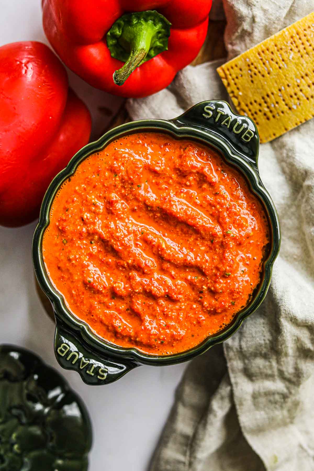 Roasted red bell pepper pesto in a green Staub cocotte, for crostini, steak, pasta, and more.
