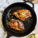 Juicy cast iron chicken breast with herbed roasted garlic butter and lemon juice in a Lodge cast iron skillet.