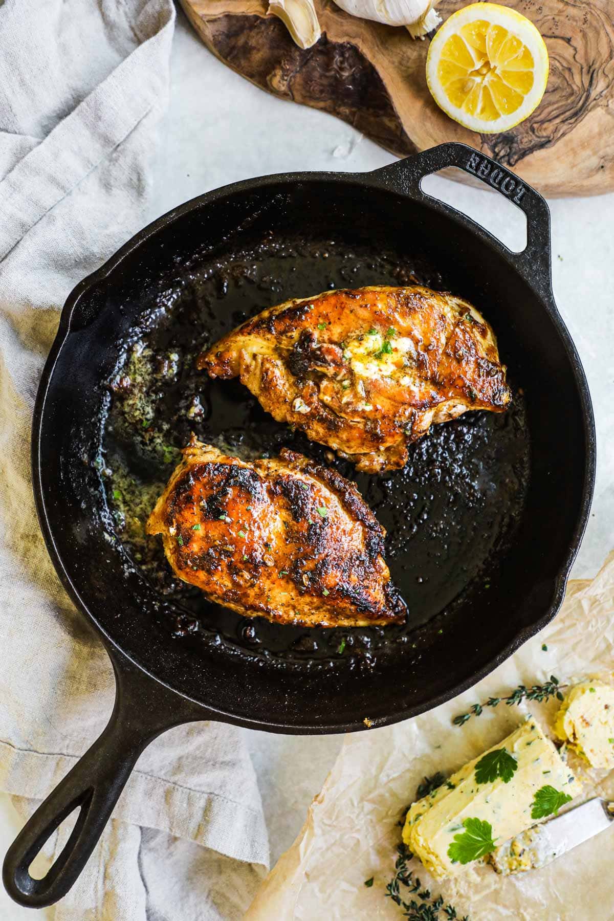 Juicy cast iron chicken breast with herbed roasted garlic butter and lemon juice in a Lodge cast iron skillet.