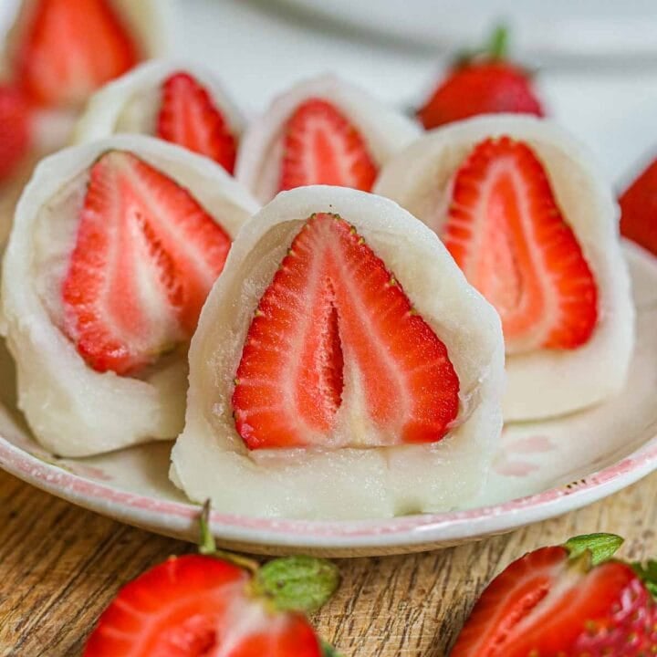 Strawberry mochi, or ichigo daifuku, stuffed with a fresh strawberry and shiroan/ anko (white bean paste) cut in half and served on a plate.