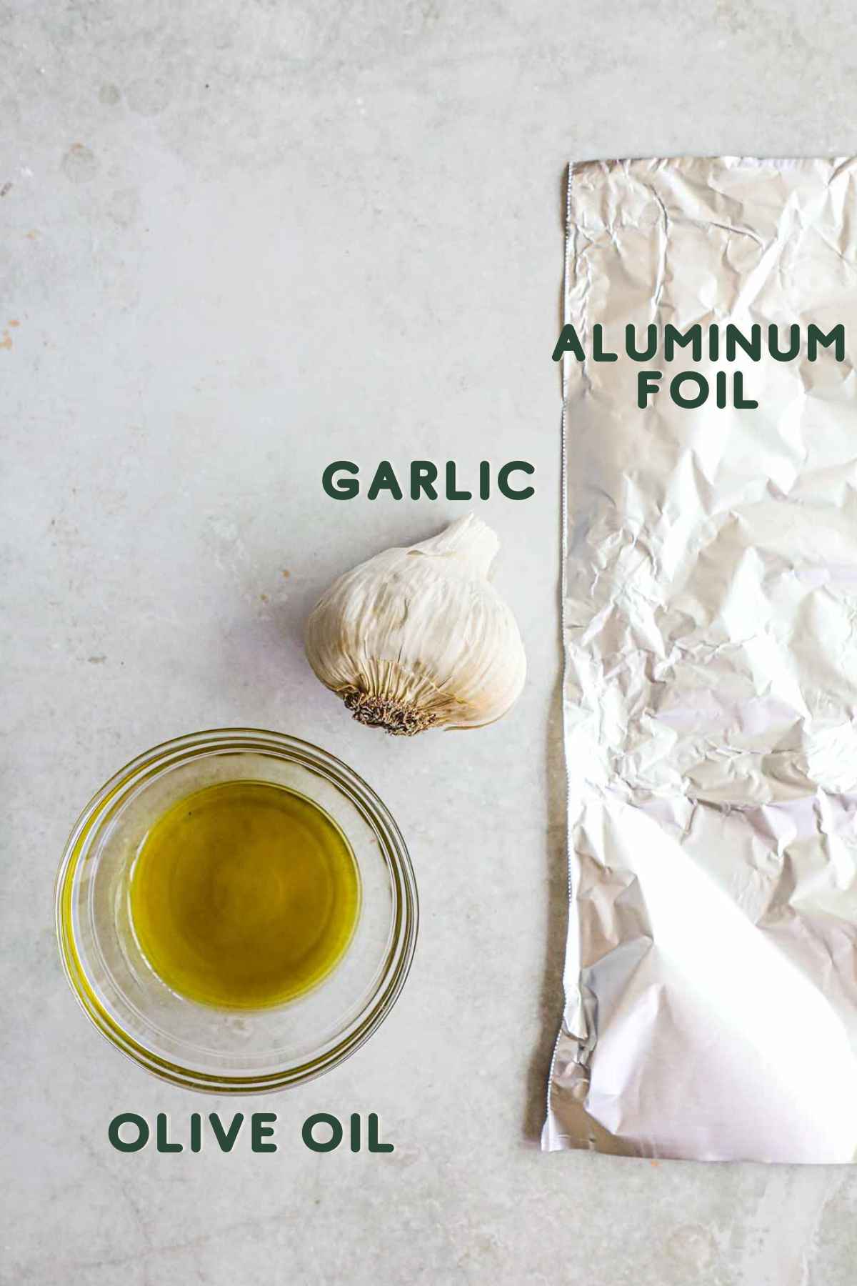 Ingredients to make oven-roasted garlic, including aluminum foil, garlic bulb, and olive oil.
