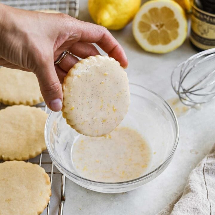 Cookie dipped in a bowl of lemon vanilla bean glaze, for cakes, scones, cookies, muffins, and more.
