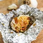 Oven-roasted garlic bulb in olive oil in aluminum foil.