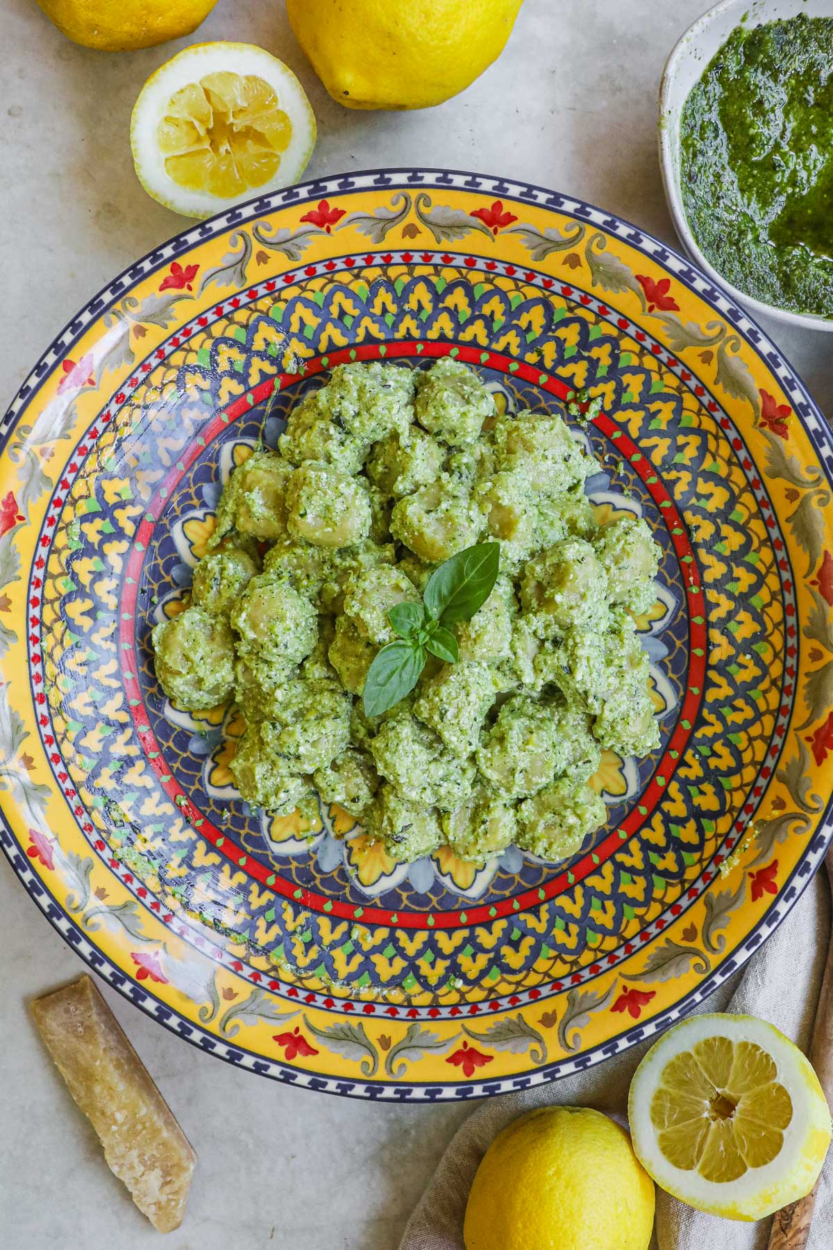 Creamy pesto gnocchi (gnocchi al pesto) in a creamy ricotta pesto with lemon zest and juice in an Italian ceramic serving bowl.