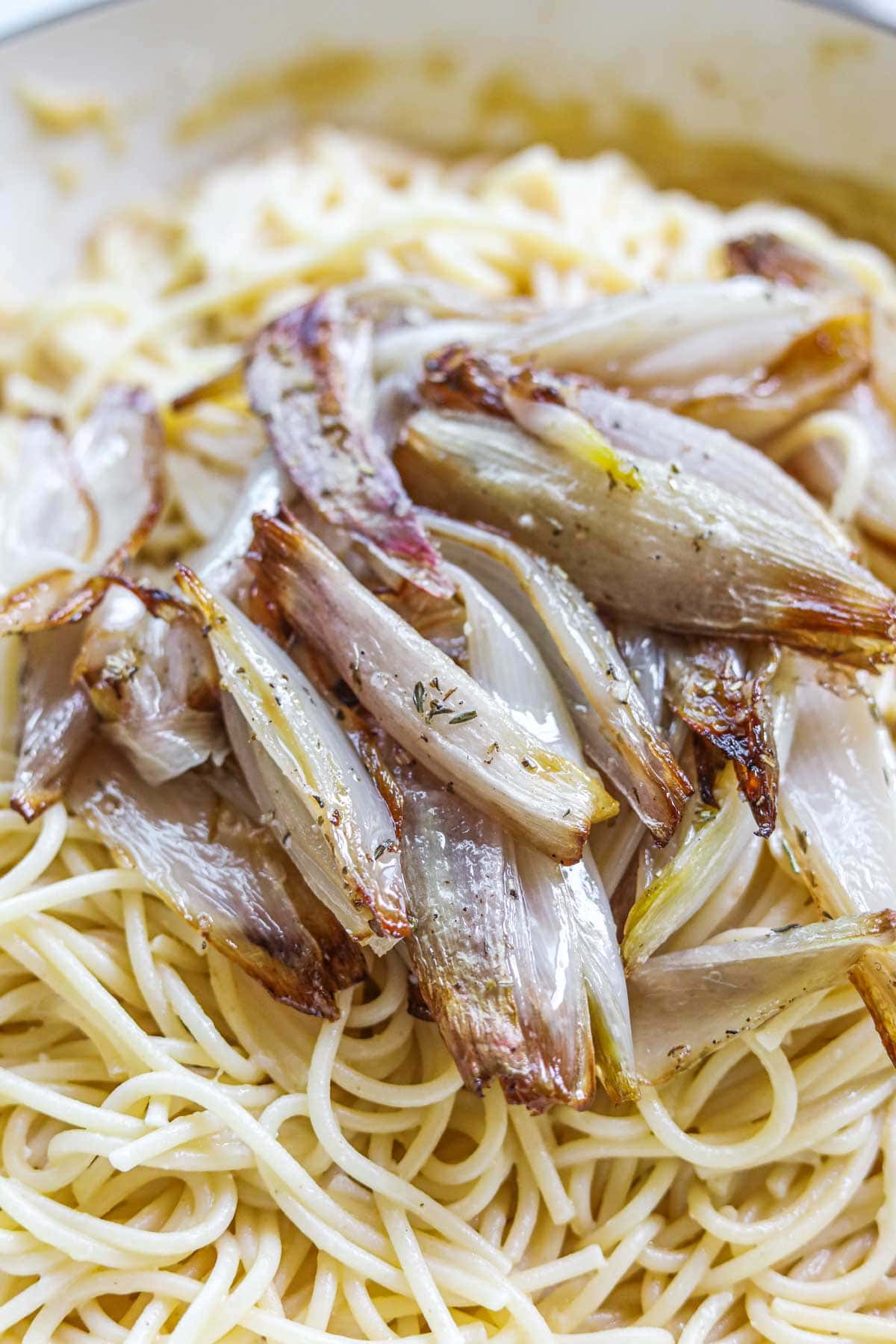 Roasted caramelized shallots with herbs on top of pasta.
