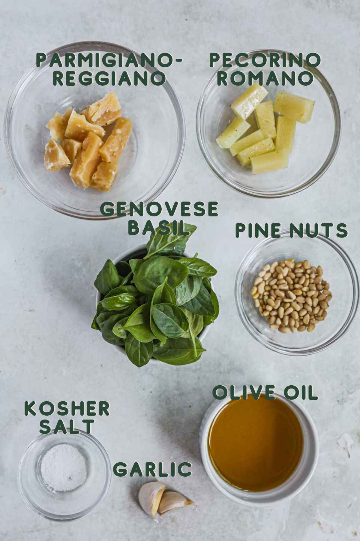 Ingredients to make pesto alla genovese (classic basil pesto), parmigiano-reggiano, pecorino romano, genovese basil, pine nuts, kosher salt, garlic, olive oil.