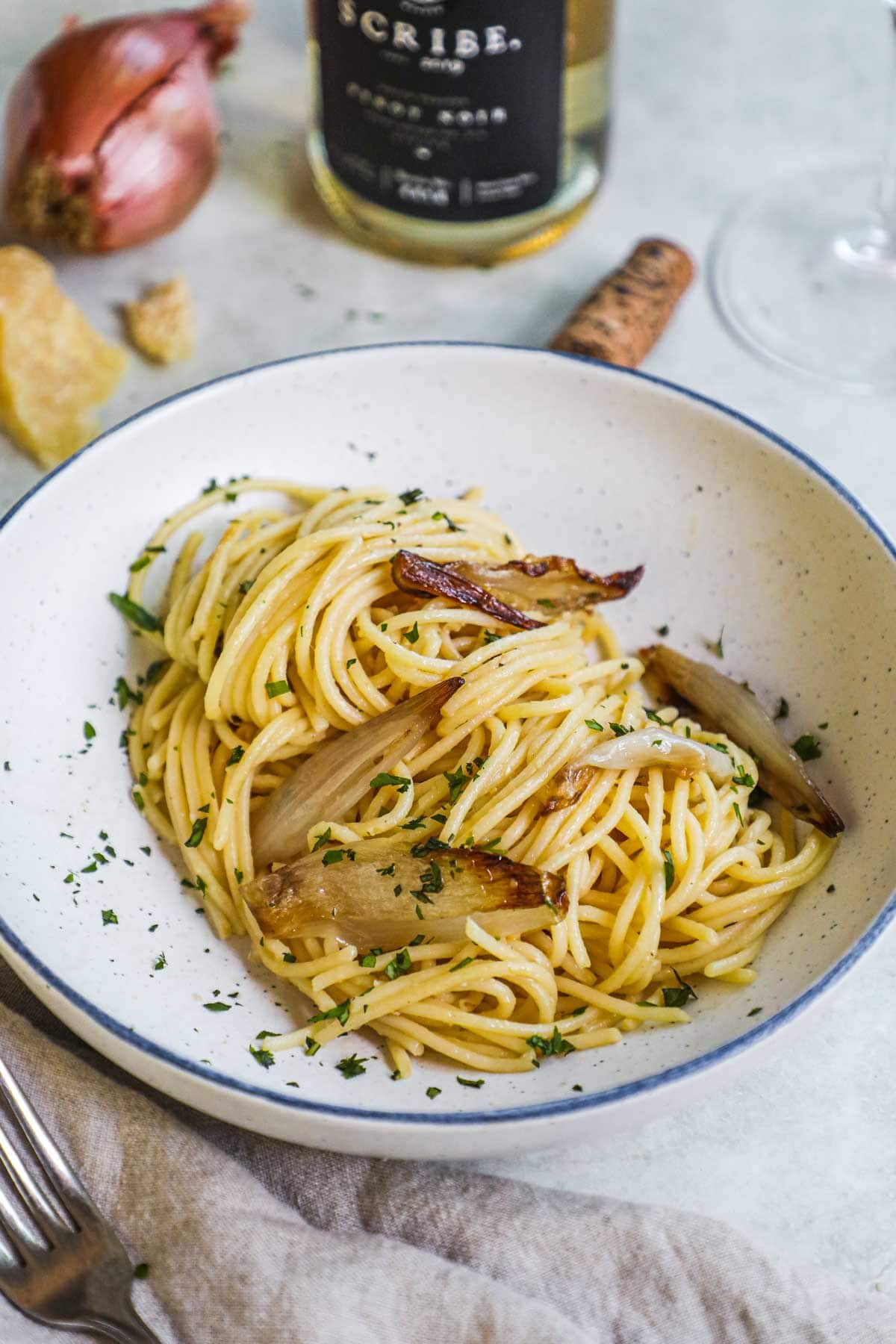 Miso spaghetti with caramelized shallots, Italian flat-leaf parlsey, and Parmigiano-Reggiano in a shallow pasta bowl.