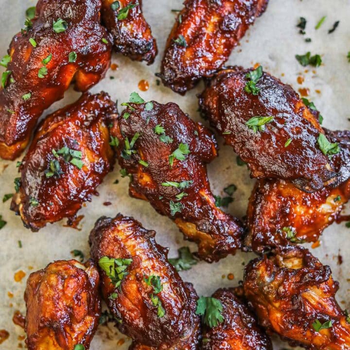 Juicy honey bbq chicken wings baked in the oven on a serving platter with chopped cilantro.