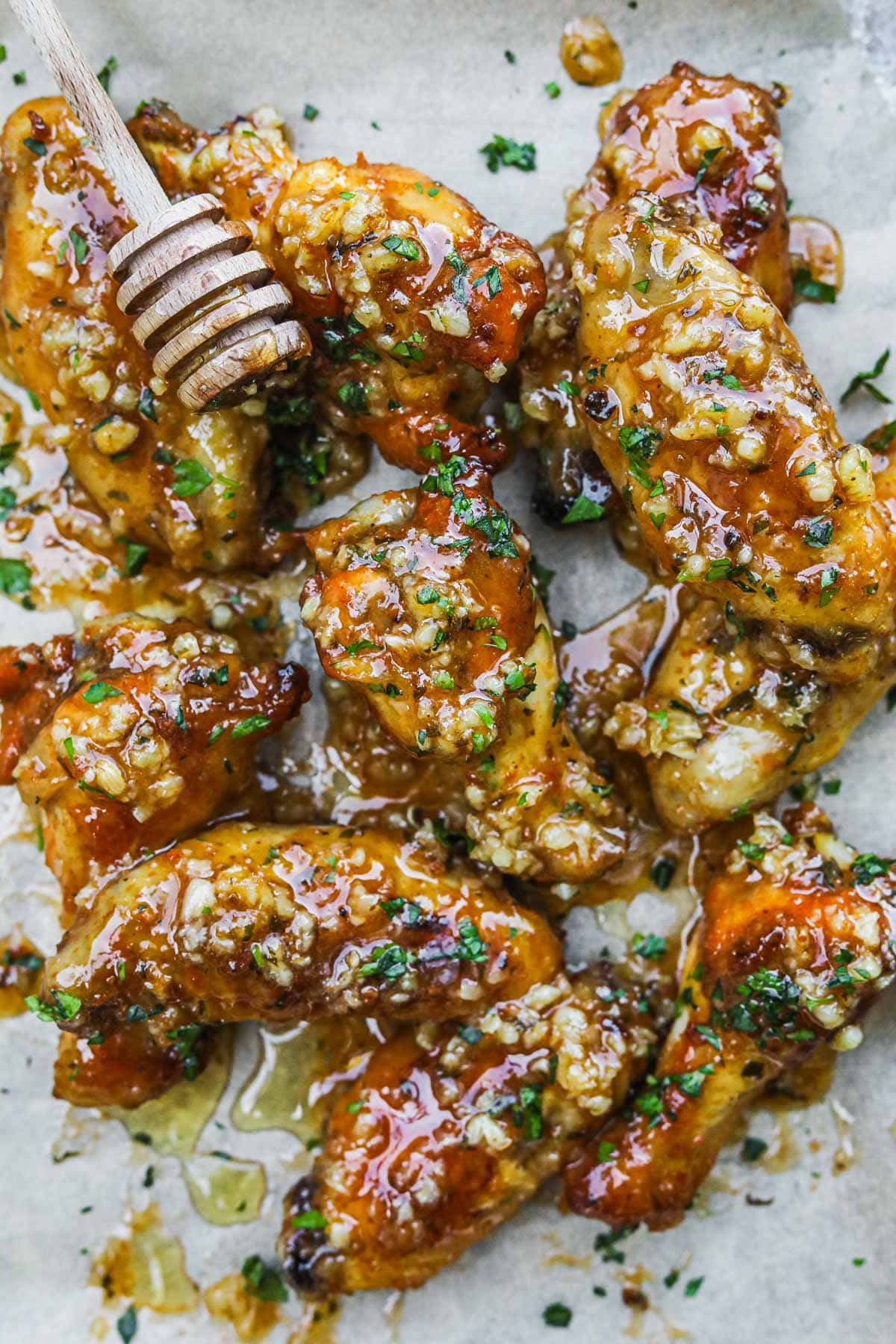 Honey garlic chicken wings smothered in a honey lemon garlic sauce with chopped parsley on a baking sheet to serve for a group.