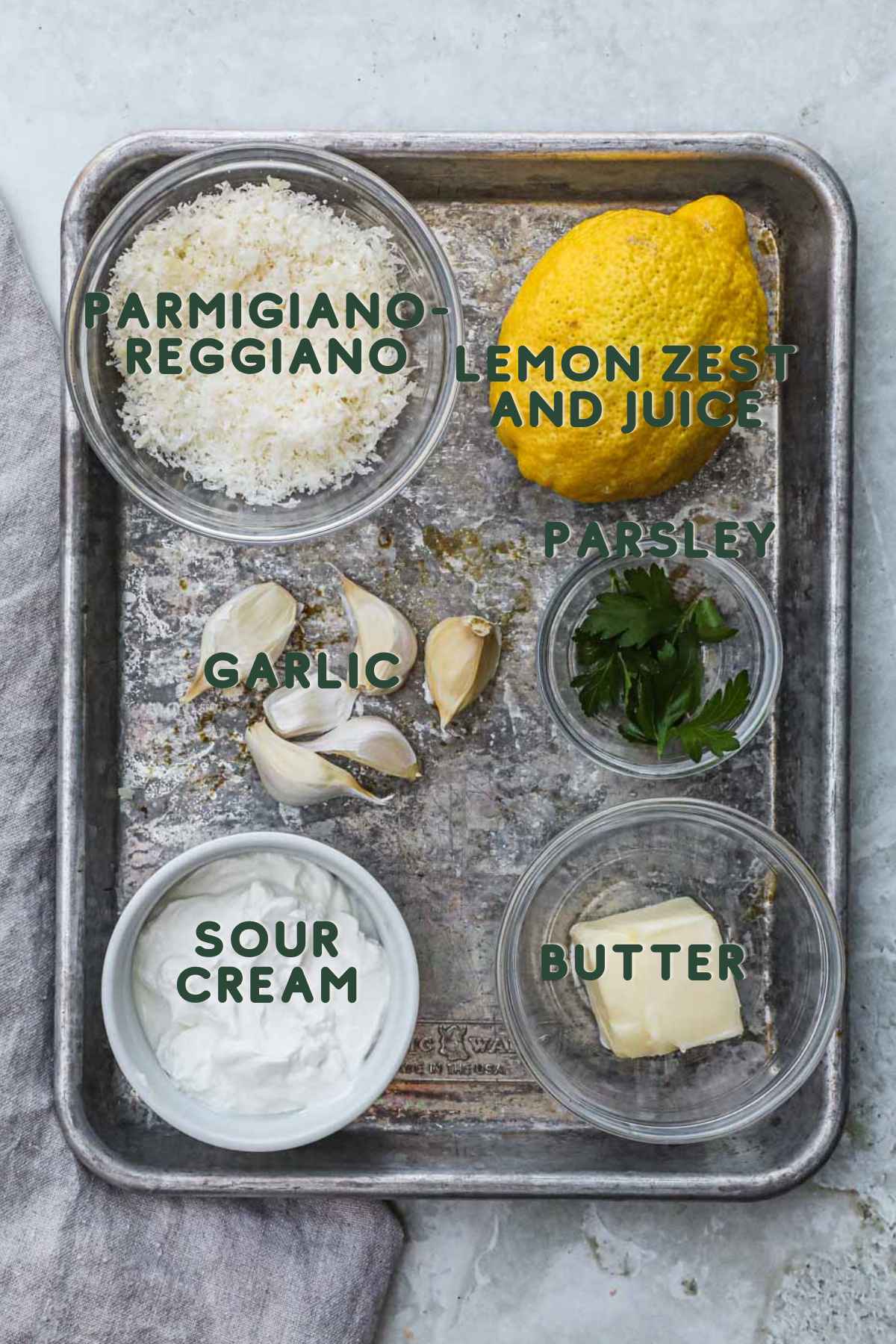 Ingredients to make garlic parmesan sauce, parmigiano-reggiano, lemon zest and juice, garlic, parsley, sour cream, butter.