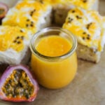Passion fruit curd in a glass weck jar with slices of passion fruit cake topped with mascarpone whipped cream, lilikoi butter, and fresh passion fruit pulp.