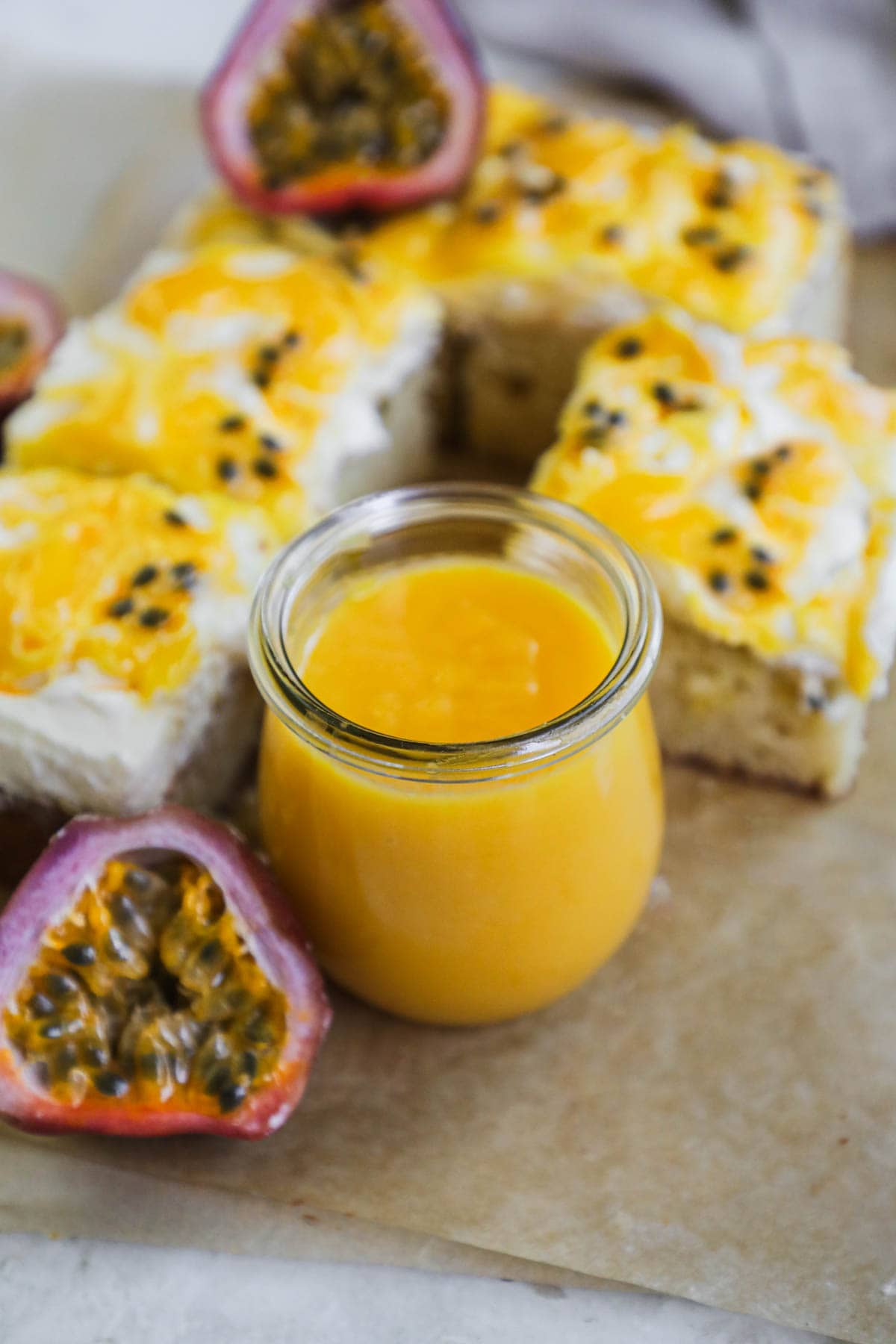 Passion fruit curd in a glass weck jar with slices of passion fruit cake topped with mascarpone whipped cream, lilikoi butter, and fresh passion fruit pulp.