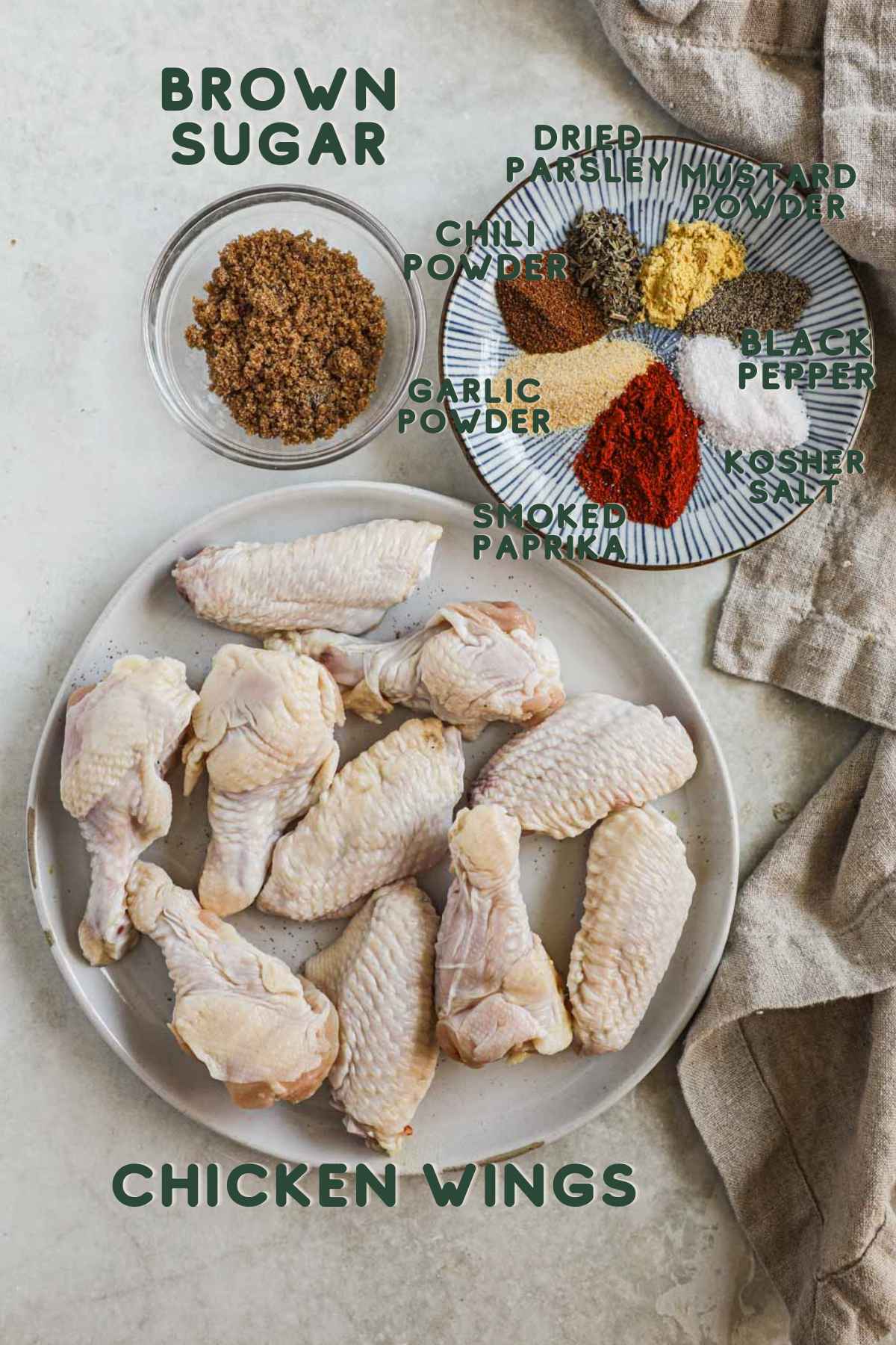Ingredients to make baked dry rub chicken wings, chicken flats and drummettes, brown sugar, parsley, mustard powder, chili powder, garlic powder, smoked paprika, black pepper, kosher salt.