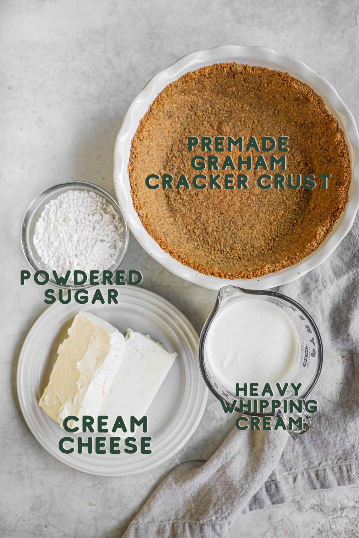 Ingredients to make no bake 3-ingredient cheesecake, premade graham cracker crust, powdered sugar, cream cheese, heavy whipping cream.