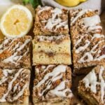Sliced lemon curd coffee cake squares with cinnamon streusel and vanilla bean glaze drizzled on top, surrounded by sliced lemons.