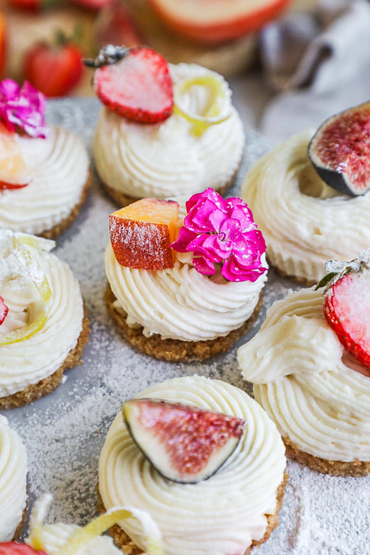 No-bake mini cheesecakes topped with fresh strawberries, figs, peaches, nectarines, and edible flowers.