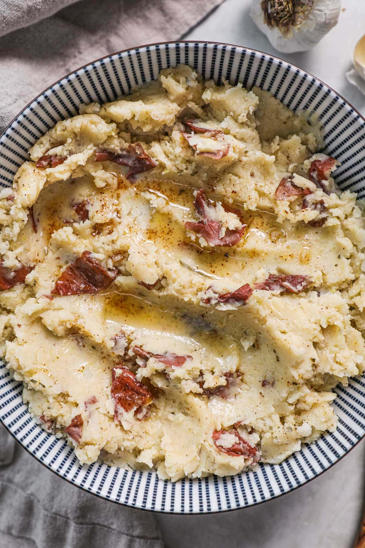 Mashed potatoes with red skin topped with a drizzle of browned butter.