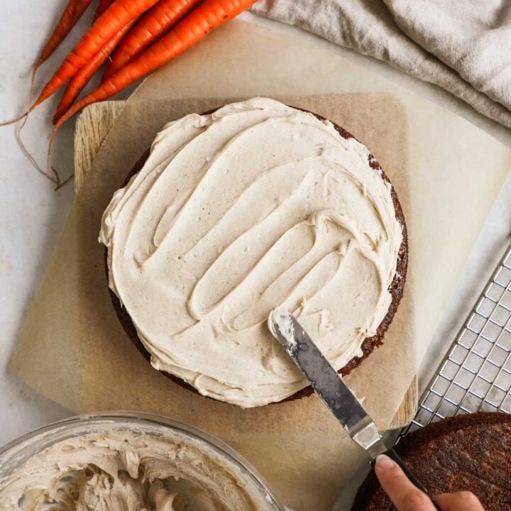 Homemade chai cream cheese frosting being spread on a carrot cake.