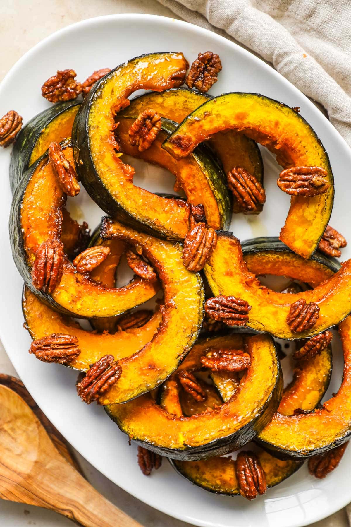 Roasted maple kabocha squash on a serving platter topped with maple-glazed cinnamon pecans.