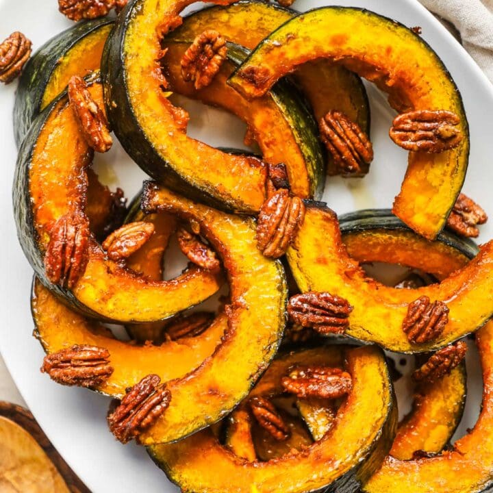 Roasted maple kabocha squash on a serving platter topped with maple-glazed cinnamon pecans.