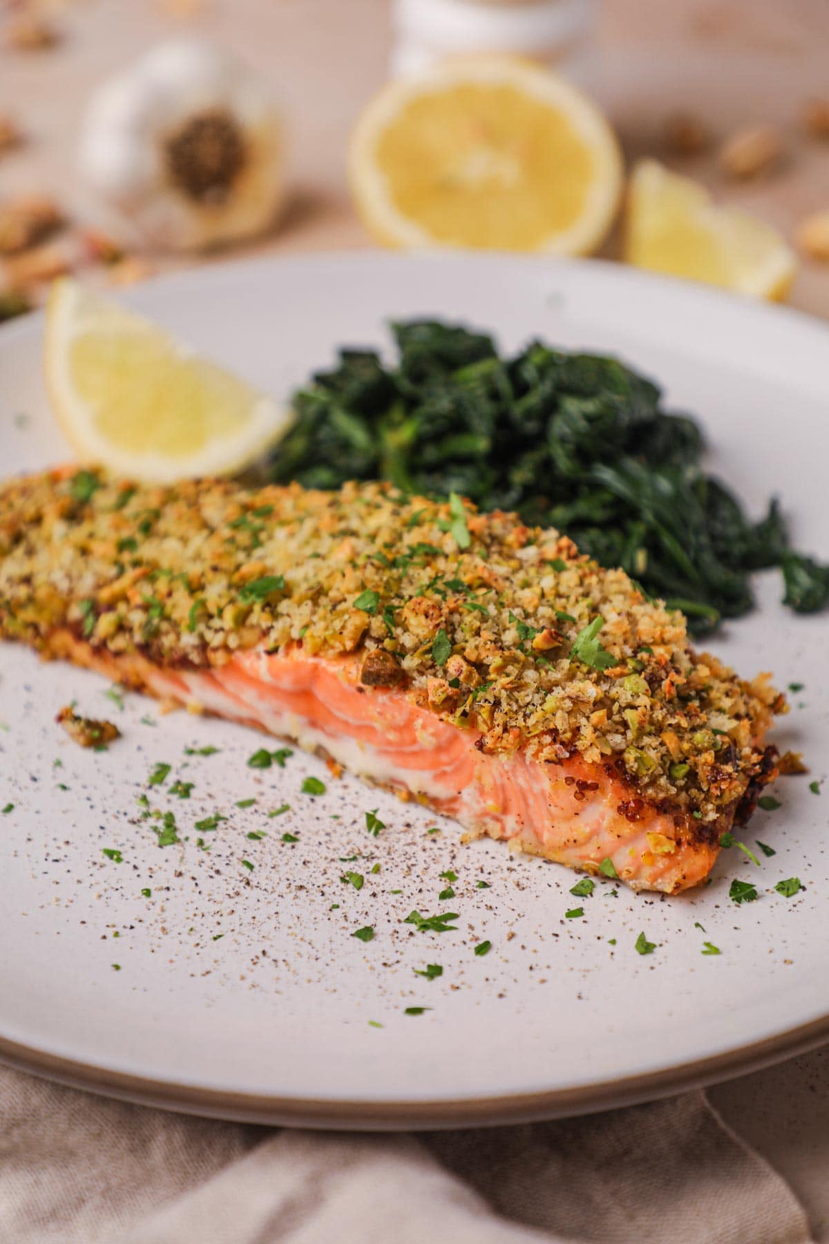 Panko and pistachio-crusted salmon filet with dijonnaise, served with sautéed spinach and lemon wedges.
