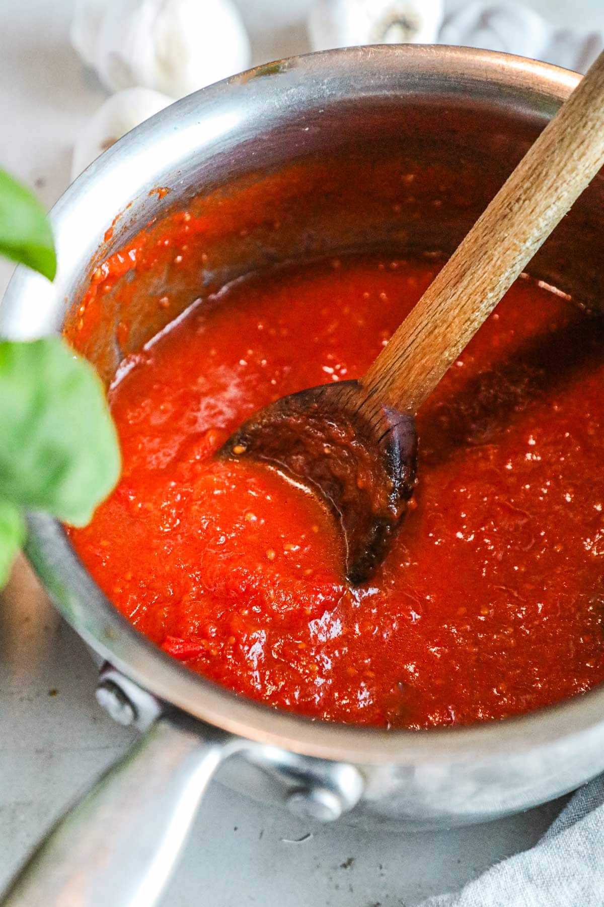 Authentic pomodoro sauce made with San Marzano tomatoes simmering in a pot, used for pasta, lasagna, pizza, eggplant parmigiana, and more.