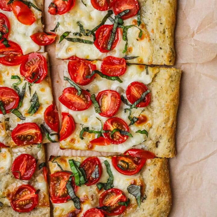 Caprese pizza made with cherry tomato, mozzarella, basil, and a homemade crust brushed with olive oil.