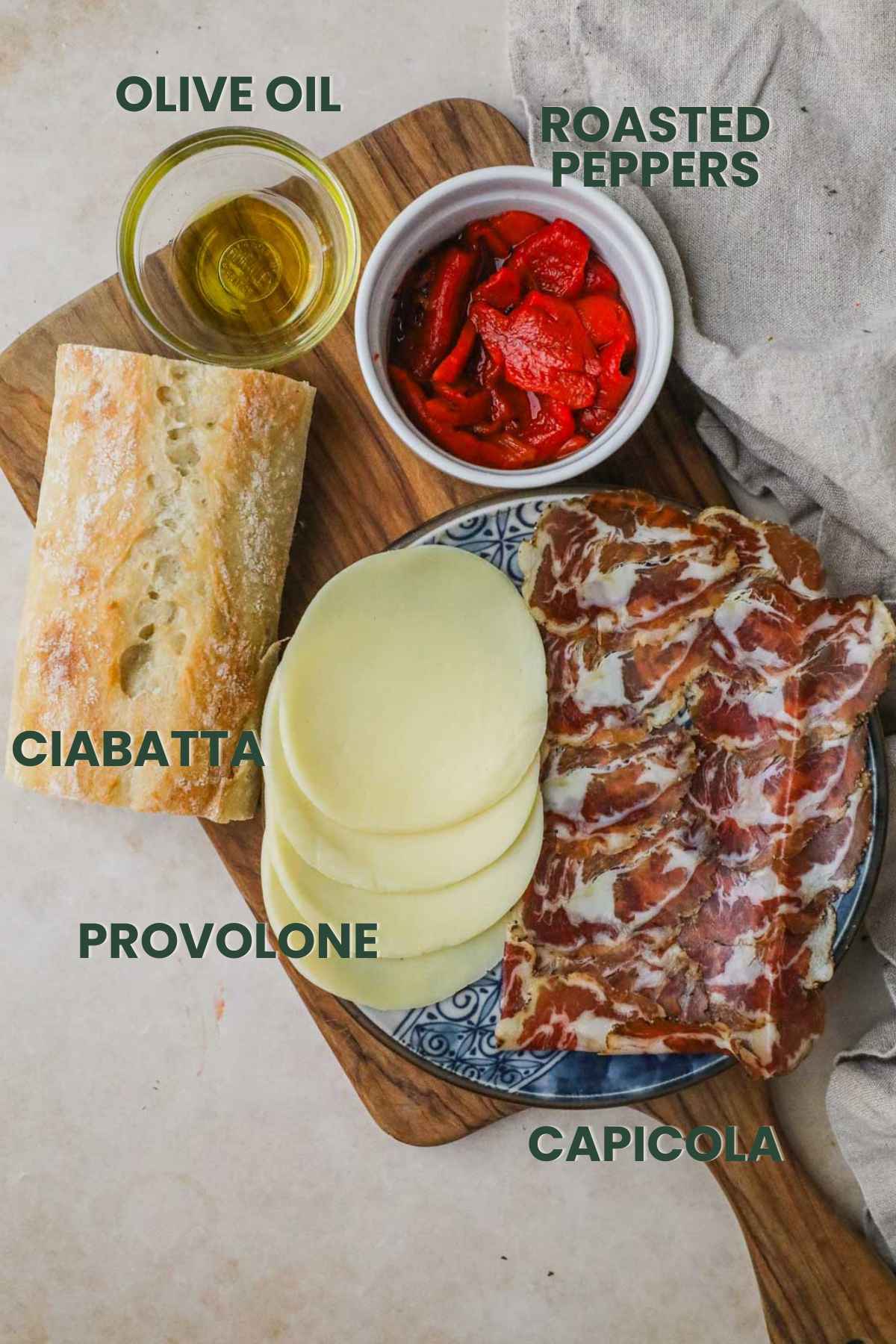 Ingredients for panino, ciabatta, olive oil, roasted peppers, provolone, and capicola.