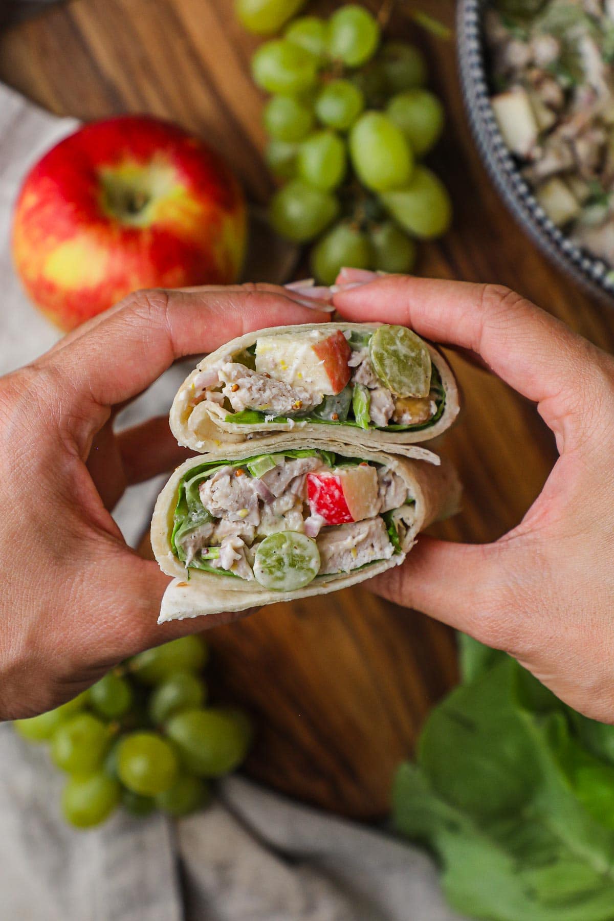 Hands holding a chicken salad wrap with lettuce for a healthy, delicious, easy lunch.