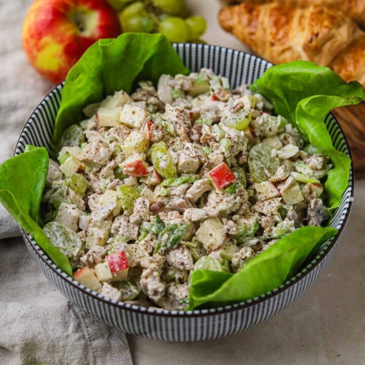 Chicken Waldorf salad with apples, grapes, and walnuts in a lettuce-lined bowl.