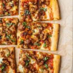 Homemade Italian sausage and caramelized onion pizza with rosemary and chili flakes on a homemade pizza dough.