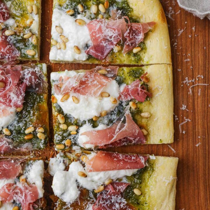 Pesto, burrata, prosciutto, and toasted pine nut pizza on a wooden Boos Block cutting board.