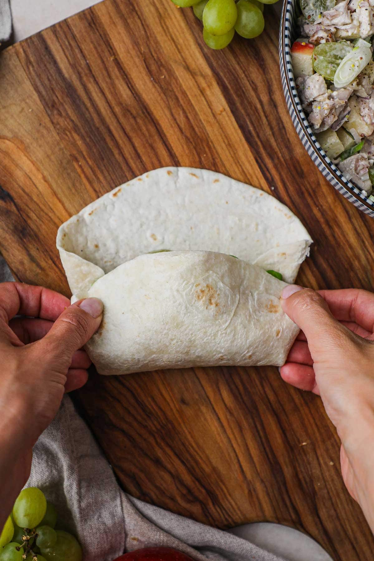 Hands holding a large tortilla to perfectly wrap a burrito or wrap.