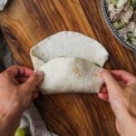 Hands holding a large tortilla to perfectly wrap a burrito or wrap.