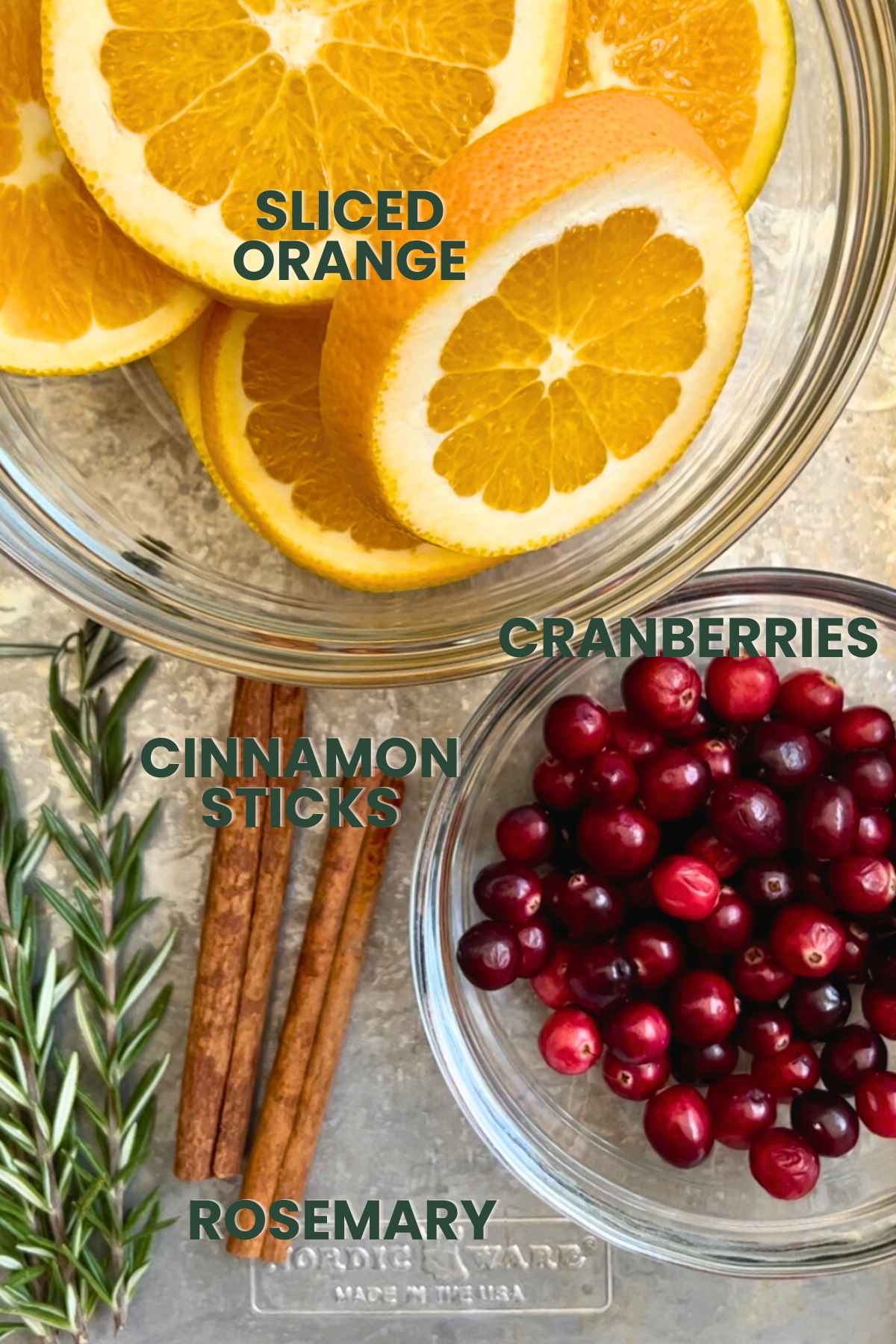 Ingredients for a Christmas holiday simmer pot, sliced orange, fresh cranberries, cinnamon sticks, rosemary.