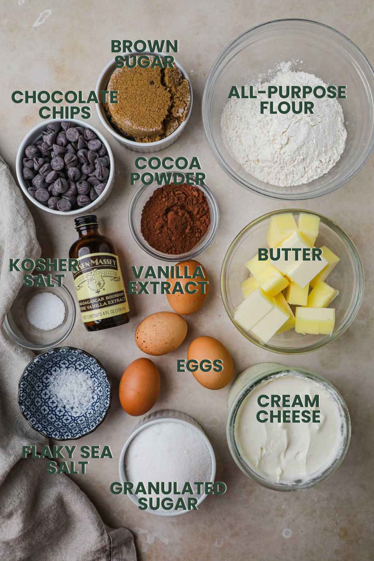 Ingredients for cheesecake brownies, flour, brown and granulated sugar, butter, cocoa powder, vanilla extract, kosher salt, cream cheese, eggs, chocolate chips.