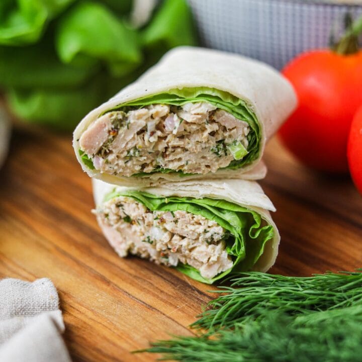 Tuna salad wrap made with lettuce and tortilla, cut in half and stacked.