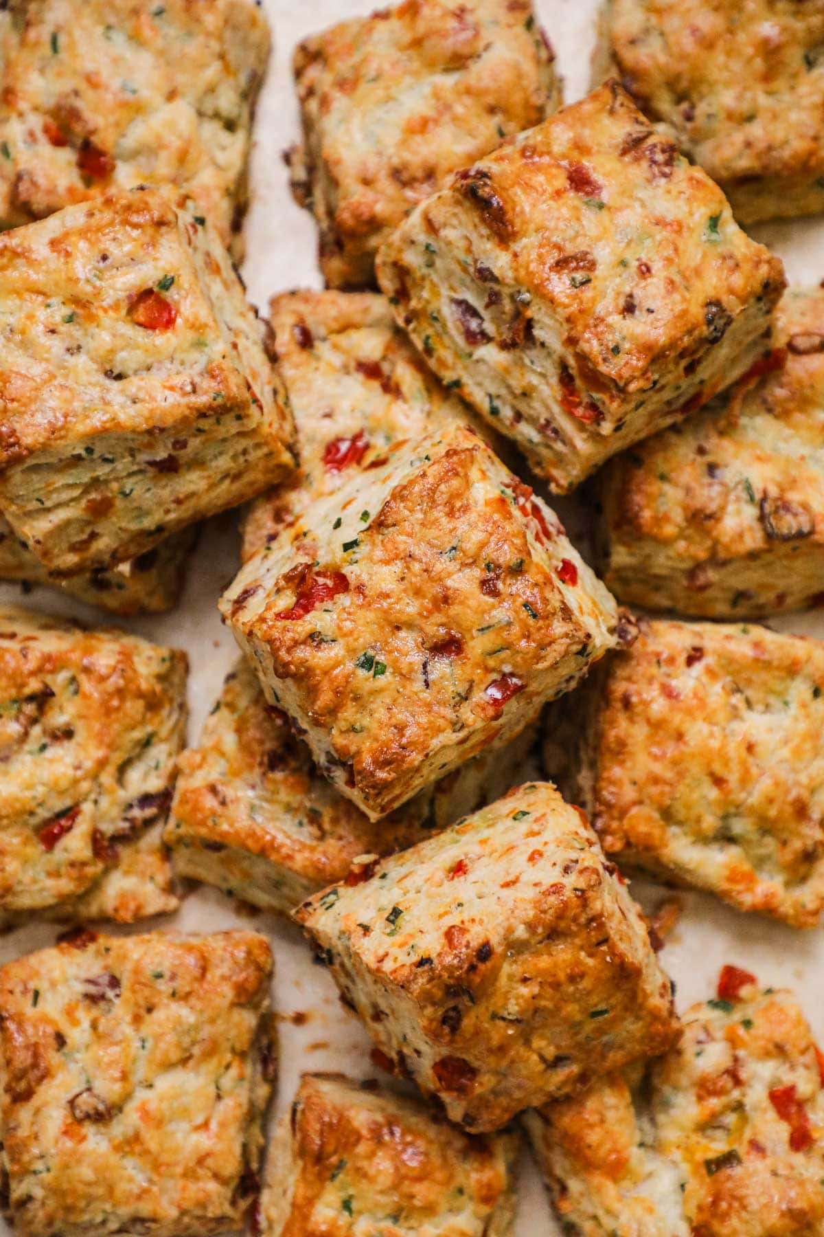 Pile of tender golden flaky bacon cheddar chive biscuits.